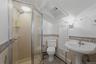 Full Bathroom in 3rd bedroom on the second level featuring a glass-enclosed shower, pedestal sink, ceramic tile flooring, and decorative wainscoting