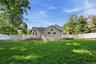 Expansive lawn area featuring a white privacy fence
