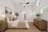 Vaulted ceiling bedroom 2 on the first level  featuring wood-finish flooring, a ceiling fan with integrated lighting, and multiple windows including t