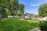 Spacious lawn area framed by a white privacy fence and mature trees