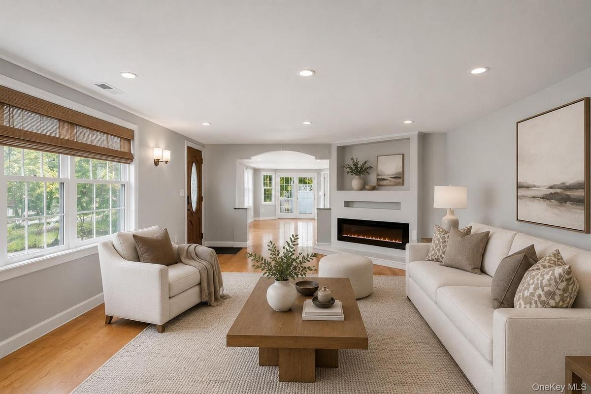 Bright living space featuring wood-finish flooring, recessed lighting, and an integrated electric fireplace with shelving above