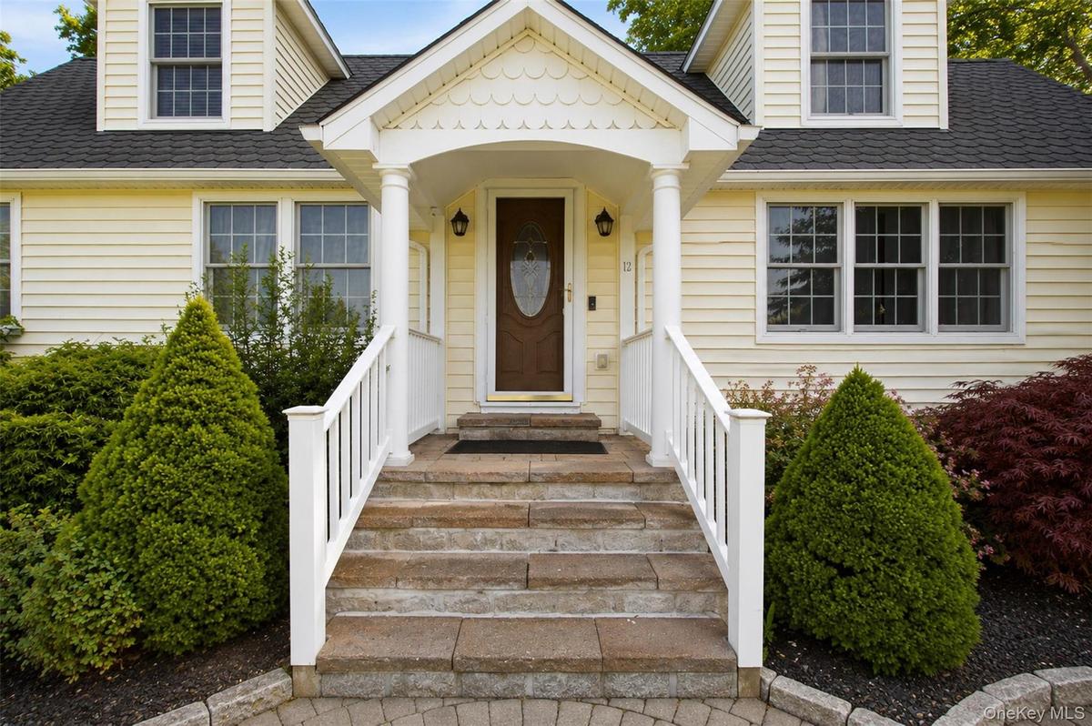 Siding exterior featuring a portico entry with white columns and railings