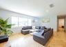 Bright living space featuring large sliding windows, light-colored tile flooring, recessed ceiling lighting, and a white entry door with frosted glass