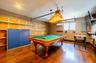 Recreation room featuring rich wood-finish flooring, a wood-framed pool table with green felt, and a suspended overhead light fixture