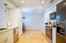 Galley kitchen featuring light-toned tile flooring, white cabinetry with gold-toned hardware, white countertops, and stainless steel appliances