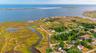 Aerial view of property and surrounding area featuring a large body of water and nearby suburban area