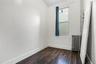 Bright room featuring wood-finish flooring, white walls, and a window with a dark curtain