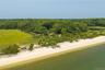 Expansive waterfront property featuring a sandy beach, mature tree line, and tranquil bay