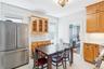 Kitchen featuring high quality fridge, tasteful backsplash, radiator, and glass insert cabinets