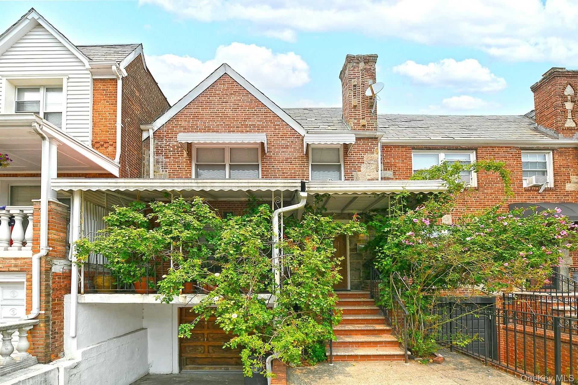 Brick facade featuring a recessed garage with a wood-finish door, a covered porch with an awning, and exterior steps leading to the entrance