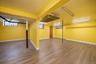 Lower level featuring wood-finish flooring, bright yellow walls, white trim, and multiple fluorescent lighting fixtures