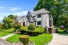 Tudor-style residence featuring a prominent front gable, stucco and half-timbering accents, a stone-clad foundation, and a slate-tile roof