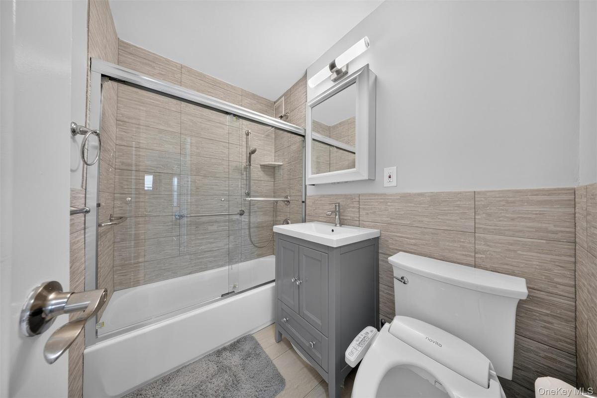 Full bathroom with tub/shower combination, vanity storage, and bidet
