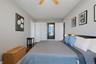 Bedroom 2 with light gray walls complement the wood-finish flooring in this room