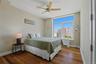 Bedroom 3 featuring wood-finish flooring, a contemporary ceiling fan, and a large window offering urban building views