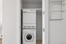 Dedicated laundry closet featuring a stacked white washer and dryer unit