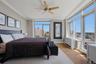 Spacious primary bedroom featuring extensive window-lines, light wood-finish flooring, and a ceiling fan