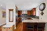 Kitchen featuring wood-finish flooring, custom wood cabinetry, stainless steel appliances, and stone countertops