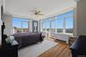 Primary bedroom with expansive window wall with cityscape and green space panorama