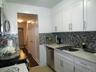 Kitchen featuring white shaker-style cabinetry, mosaic tile backsplash, stainless steel appliances, a double basin sink with a high-arc faucet, and li