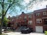 Brick rowhouse featuring a pitched roof, front entry awning, and a ground-level garage