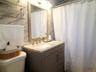 Bathroom featuring a single vanity with a light-colored countertop and integrated sink, framed mirror, and warm metallic faucet