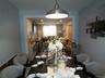 Dining area featuring a dark wood-finish table, upholstered seating, and a brushed metal pendant light fixture