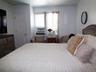 Bedroom featuring a multi-panel door, window with blinds and drapes, and a built-in air conditioning unit