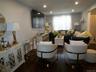 Spacious living area featuring dark wood-finish flooring, recessed lighting, and a large window with privacy blinds