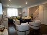 Spacious living area featuring dark wood-finish flooring, recessed lighting, and a window with blinds and sheer curtains