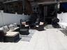 Spacious patio featuring light-toned tile flooring, white vinyl fencing, and a brick exterior with a protective awning