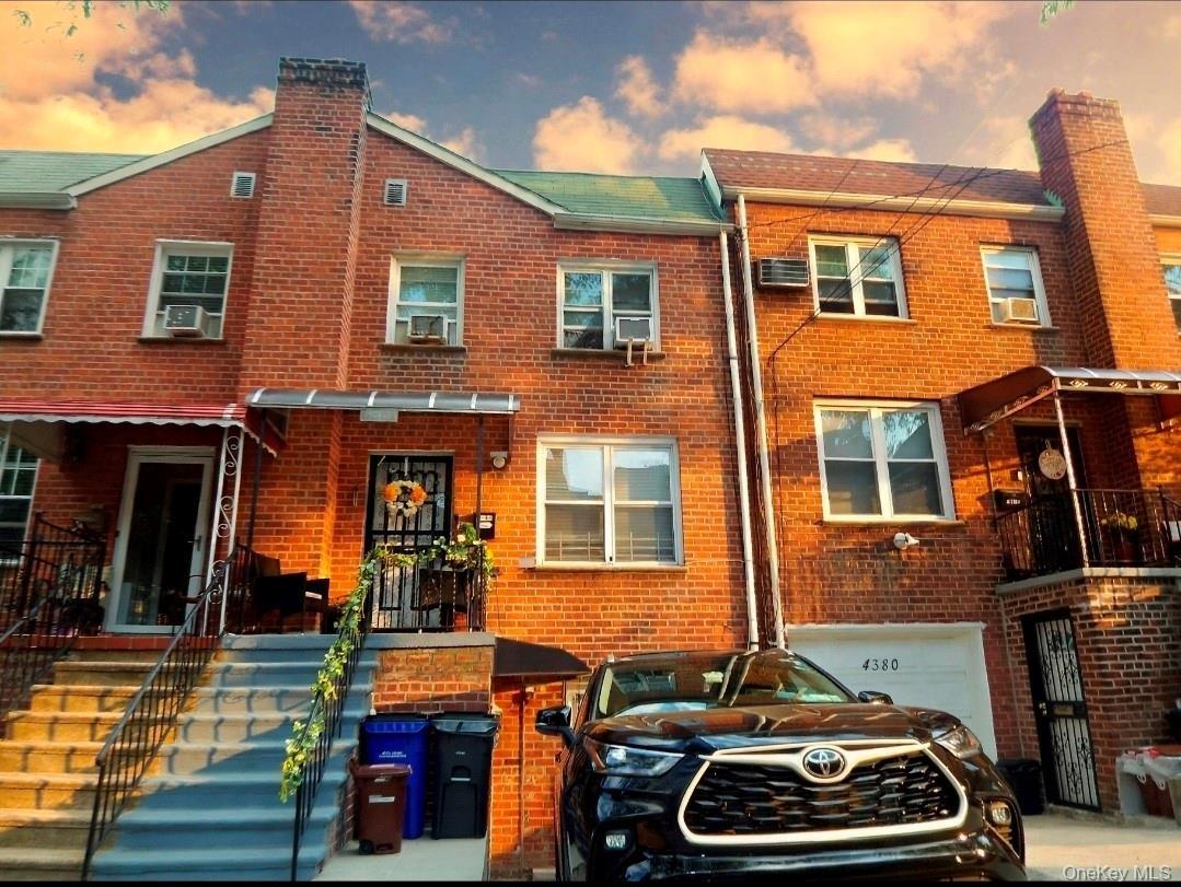 Brick facade home featuring a prominent chimney, gabled roofline, and front entry stairs with wrought iron railings