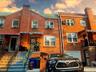 Brick facade home featuring a prominent chimney, gabled roofline, and front entry stairs with wrought iron railings