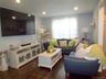 Living area featuring recessed lighting, a large window with sheers, wood-finish flooring, and light blue walls