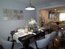 Dining area featuring dark wood-finish flooring, a contemporary pendant light fixture, and an open doorway to an adjacent living space