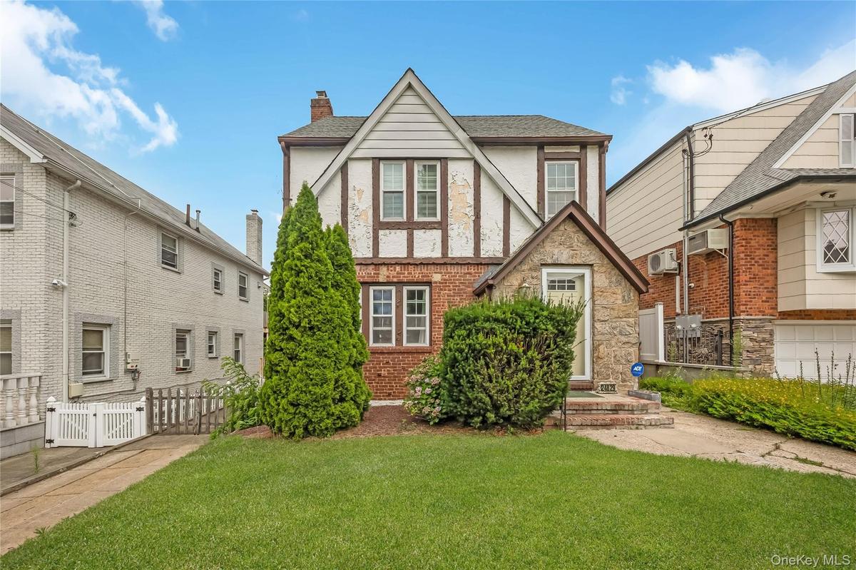 Tudor-style facade featuring brick, stone, and stucco finishes with decorative timber framing
