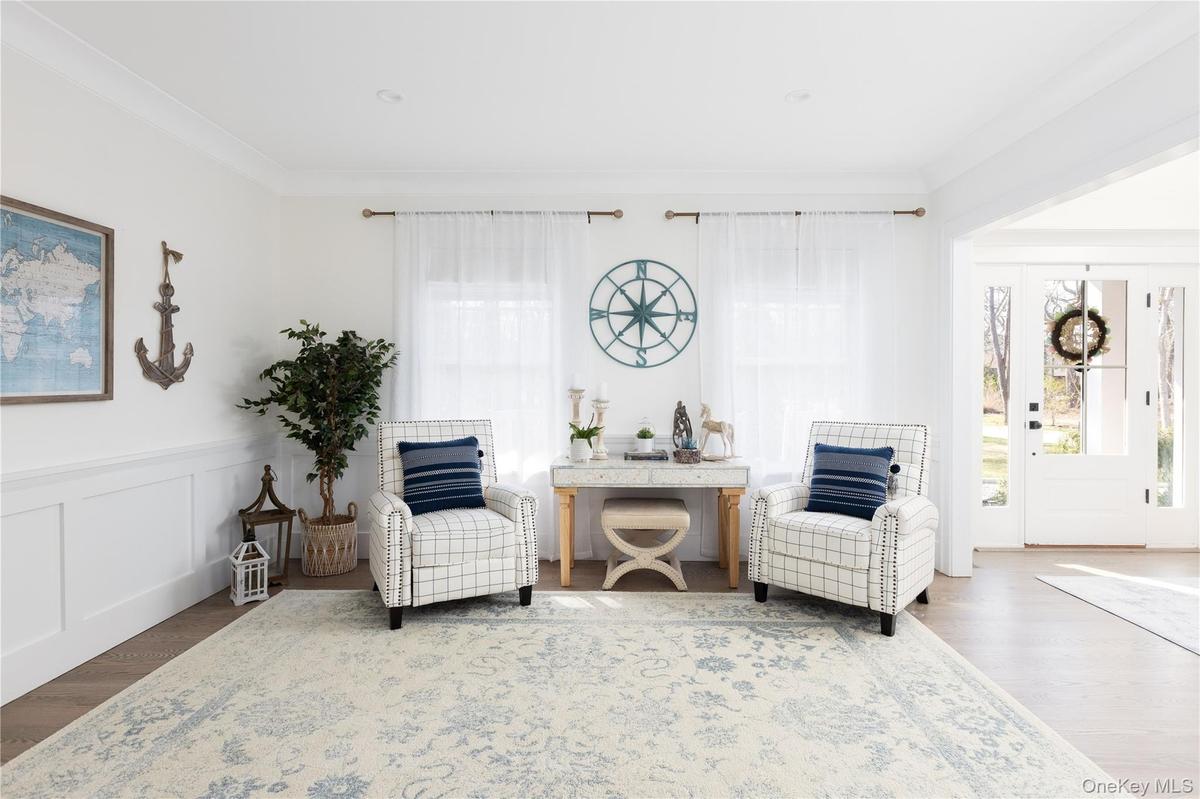 Living area with wood finished floors, ornamental molding, wainscoting, and a decorative wall