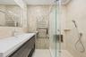 Full bathroom with a stall shower, vanity, tile walls, a towel warmer, and light tile patterned flooring