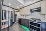 Kitchen featuring stainless steel appliances, ventilation hood, tasteful backsplash, light stone countertops, and recessed lighting