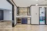 Indoor dry bar with glass insert cabinets, crown molding, wine cooler, light stone counters, and stainless steel range