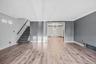 Unfurnished living room featuring a chandelier, light wood finished floors, crown molding, radiator heating unit, and a baseboard radiator