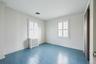 Unfurnished bedroom featuring multiple windows, crown molding, radiator, and dark wood-style flooring