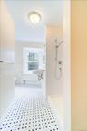 Bathroom with radiator heating unit, toilet, and tiled shower