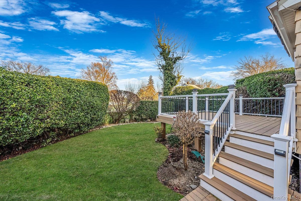 View of grassy yard featuring a deck and stairway