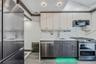 Kitchen featuring appliances with stainless steel finishes, backsplash, white cabinetry, light stone counters, and gray cabinetry