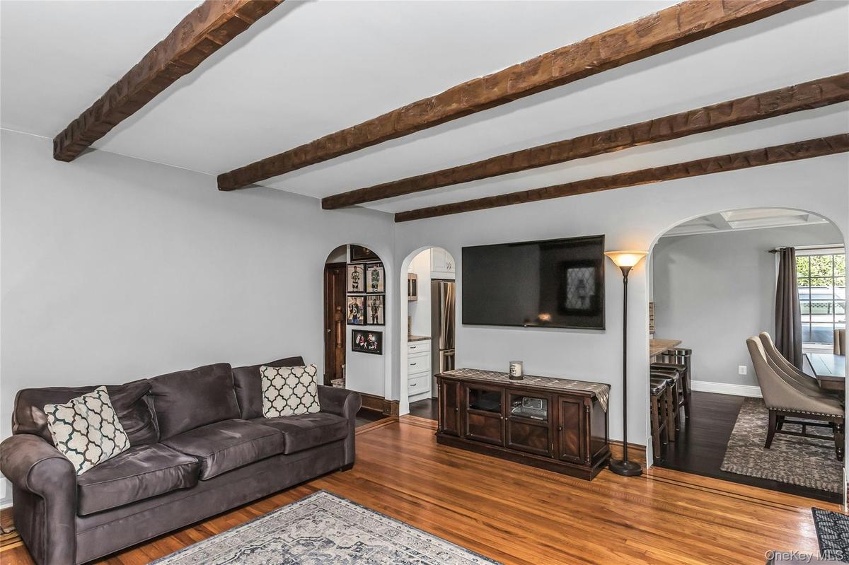 Spacious Living Room with woodburning fireplace, beamed ceiling, wood floors and exquisite details throughout