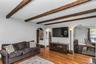 Spacious Living Room with woodburning fireplace, beamed ceiling, wood floors and exquisite details throughout