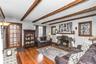 Spacious Living Room with woodburning fireplace, beamed ceiling, wood floors and exquisite details throughout