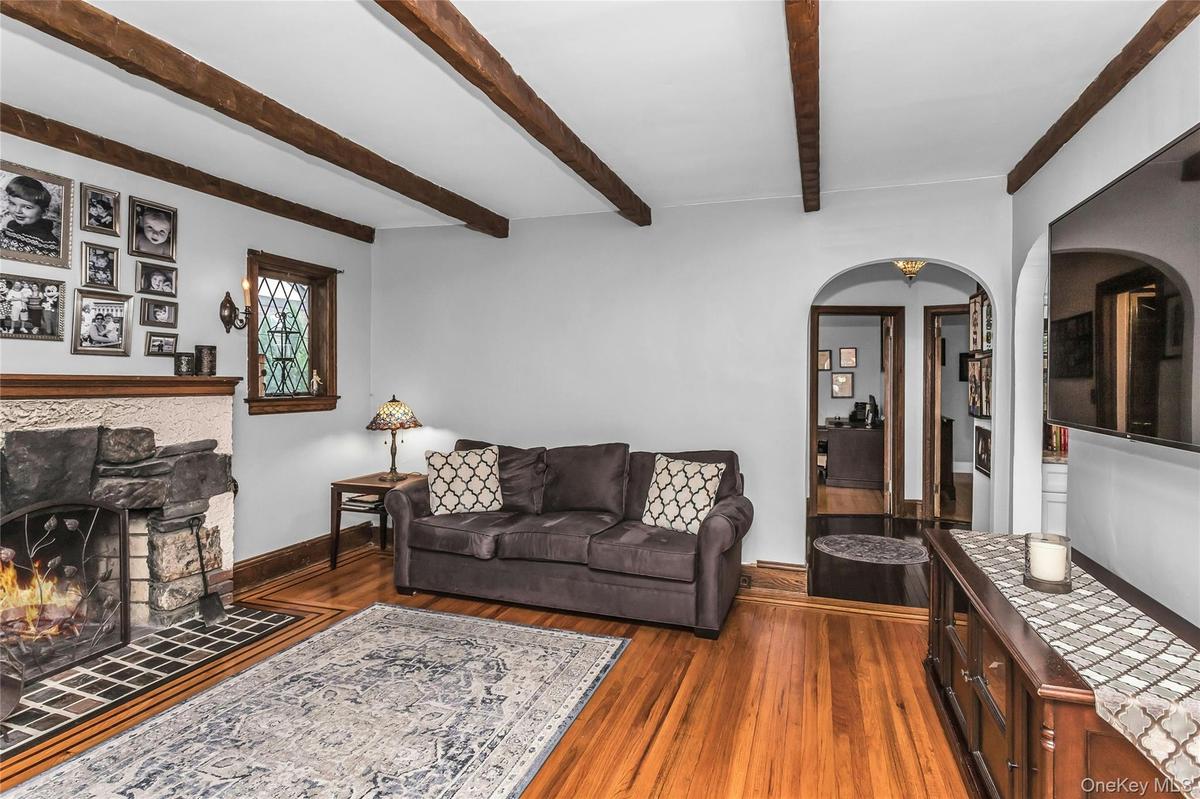 Spacious Living Room with woodburning fireplace, beamed ceiling, wood floors and exquisite details throughout