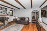 Spacious Living Room with woodburning fireplace, beamed ceiling, wood floors and exquisite details throughout